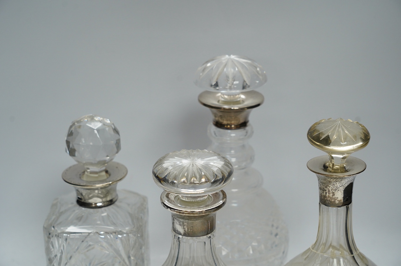 Four silver mounted glass decanters and stoppers, largest 29cm high. Condition - fair to good, one diseased